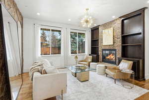 Living room with built in features, a chandelier, a fireplace, wood finished floors, and recessed lighting