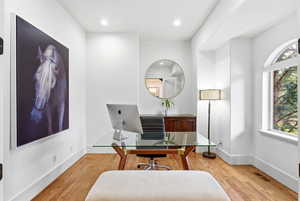 Office area with light wood-style floors and recessed lighting