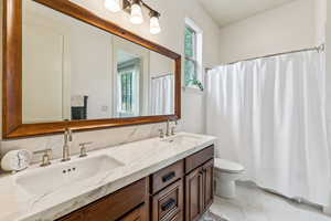 Bathroom with double vanity, tile patterned flooring, and curtained shower