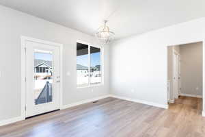 Empty room with a chandelier and light wood finished floors