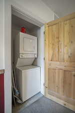 Washroom featuring stacked washing machine and dryer and tile patterned floors