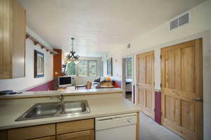Kitchen featuring dishwasher, carpet floors, open floor plan, light countertops, and pendant lighting