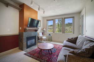 Living area featuring a tiled fireplace and carpet floors