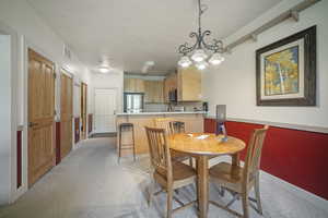 Dining space with light carpet and a chandelier