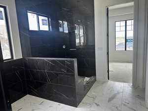 Full bath featuring a walk in shower and marble finish floors