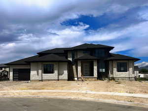 Prairie-style home featuring an attached garage, stone siding, and driveway