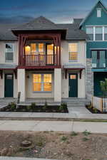 View of front facade featuring a standing seam roof, a balcony, stucco siding, and a shingled roof