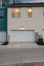View of front of property with stucco siding, an attached garage, and concrete driveway