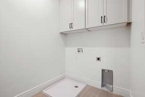 Washroom with electric dryer hookup, washer hookup, cabinet space, and tile patterned flooring