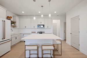 Kitchen featuring white appliances, open shelves, a breakfast bar area, decorative backsplash, and light wood-style flooring