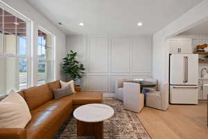 Living room featuring a decorative wall, light wood-style floors, and recessed lighting