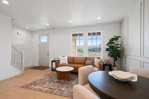Living room featuring light wood finished floors, recessed lighting, and stairway