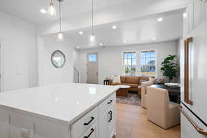 Kitchen featuring high end fridge, light wood-type flooring, recessed lighting, white cabinetry, and pendant lighting