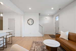Living room with stairway, light wood-style floors, and recessed lighting