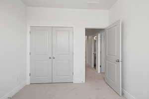 Unfurnished bedroom with light colored carpet and a closet