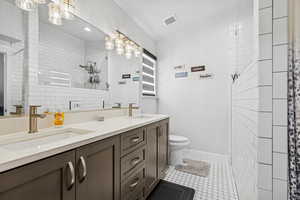 Bathroom featuring double vanity, a tile shower, tile patterned floors, and a textured ceiling