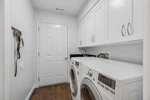Laundry area featuring cabinet space, dark wood-style floors, and washing machine and clothes dryer