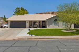 Single story home with a tile roof, a garage, a front yard, and stucco siding