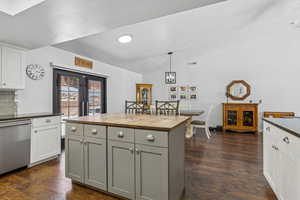 Kitchen featuring stainless steel dishwasher, butcher block counters, vaulted ceiling, a textured ceiling, and dark wood-style floors