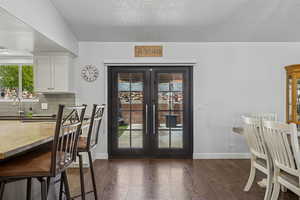 Dining area with french doors, dark wood finished floors, and a textured ceiling