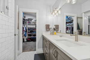 Bathroom featuring double vanity, a walk in closet, and a chandelier