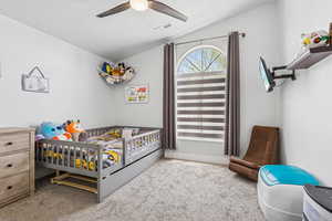 Carpeted bedroom with vaulted ceiling, a textured ceiling, and a ceiling fan