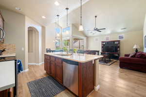 Kitchen with appliances with stainless steel finishes, open floor plan, vaulted ceiling, light wood finished floors, and ceiling fan