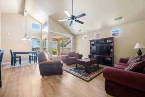 Living area featuring wood finished floors, a ceiling fan, high vaulted ceiling, and a textured ceiling