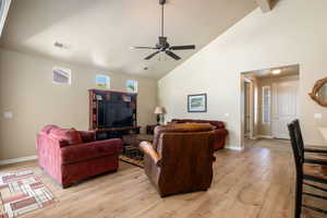 Living area featuring light wood-style floors, high vaulted ceiling, and ceiling fan