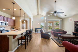 Kitchen with stainless steel appliances, open floor plan, a textured ceiling, a breakfast bar area, and light wood-type flooring