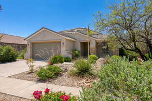 Ranch-style home with stucco siding, driveway, a garage, stone siding, and a tiled roof