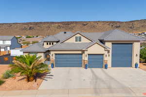 View of front of house featuring stucco siding, a garage, concrete driveway, a mountain view, and a tile roof