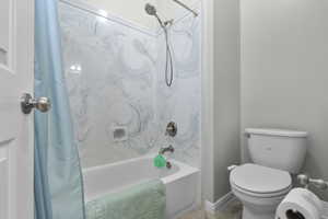 Full bathroom featuring shower / tub combo with curtain and toilet