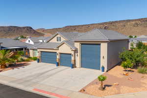 View of front of house featuring stucco siding, a mountain view, a tile roof, and concrete driveway