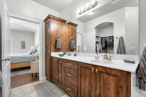 Ensuite bathroom featuring double vanity, tile patterned flooring, and a spacious closet