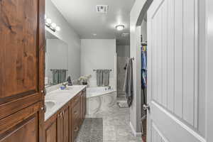 Full bathroom with a bath, double vanity, and a closet