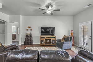 Living room featuring arched walkways, ceiling fan, and wood finished floors