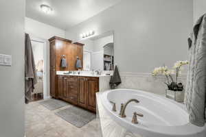 Bathroom with a bath, double vanity, and tile patterned floors