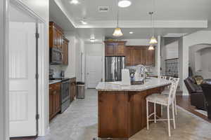 Kitchen with stainless steel appliances, backsplash, a kitchen bar, light stone countertops, and decorative light fixtures