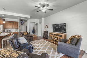 Living room featuring arched walkways, ceiling fan, and wood finished floors