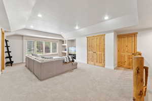 Living room featuring vaulted ceiling, carpet flooring, recessed lighting, and built in shelves