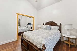 Bedroom with vaulted ceiling, dark wood-style floors, and a ceiling fan
