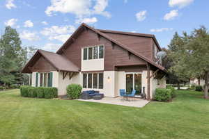 Rear view of house with a patio area, a yard, and stucco siding
