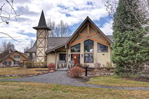 View of front of home with stucco siding, a front yard, and roof with shingles