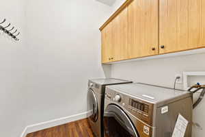 Laundry room with cabinet space, independent washer and dryer, and dark wood finished floors