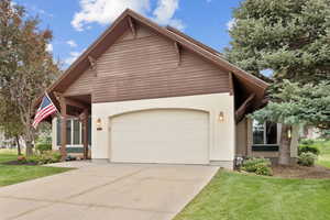 View of front of property featuring stucco siding, an attached garage, concrete driveway, and a front yard