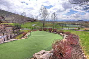 View of yard with a putting area, a mountain view, and a tennis court