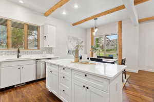 Kitchen with stainless steel dishwasher, beam ceiling, dark wood finished floors, recessed lighting, and tasteful backsplash