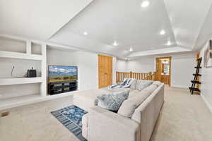 Living area featuring light colored carpet, recessed lighting, built in features, a tray ceiling, and lofted ceiling