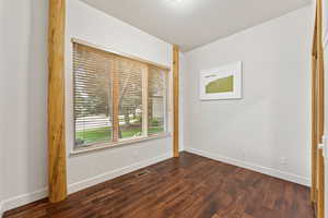Unfurnished bedroom featuring baseboards and dark wood-style flooring